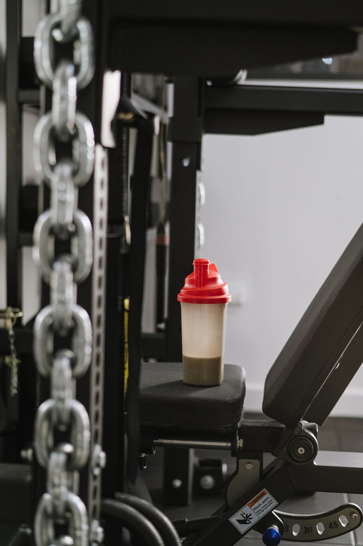 Bote de proteina o creatina apoyado sobre una máquina de gimnasio