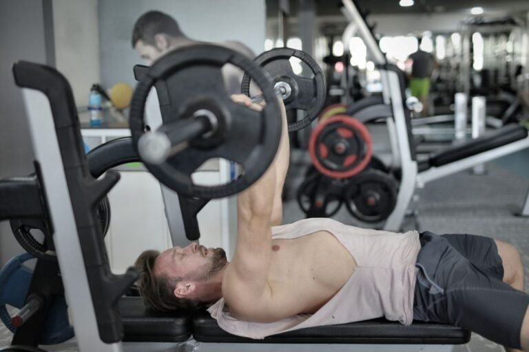 Hombre realizando press banca con barra en un gimnasio moderno
