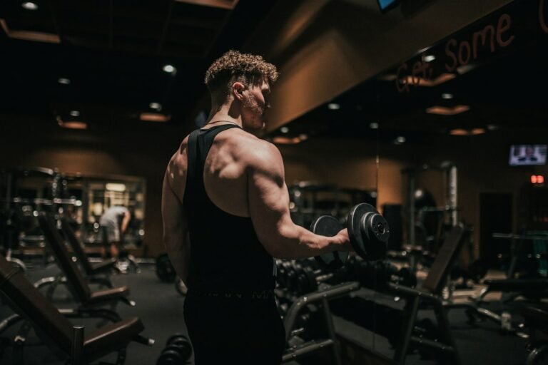 Hombre haciendo curl de bíceps con mancuerna en el gimnasio