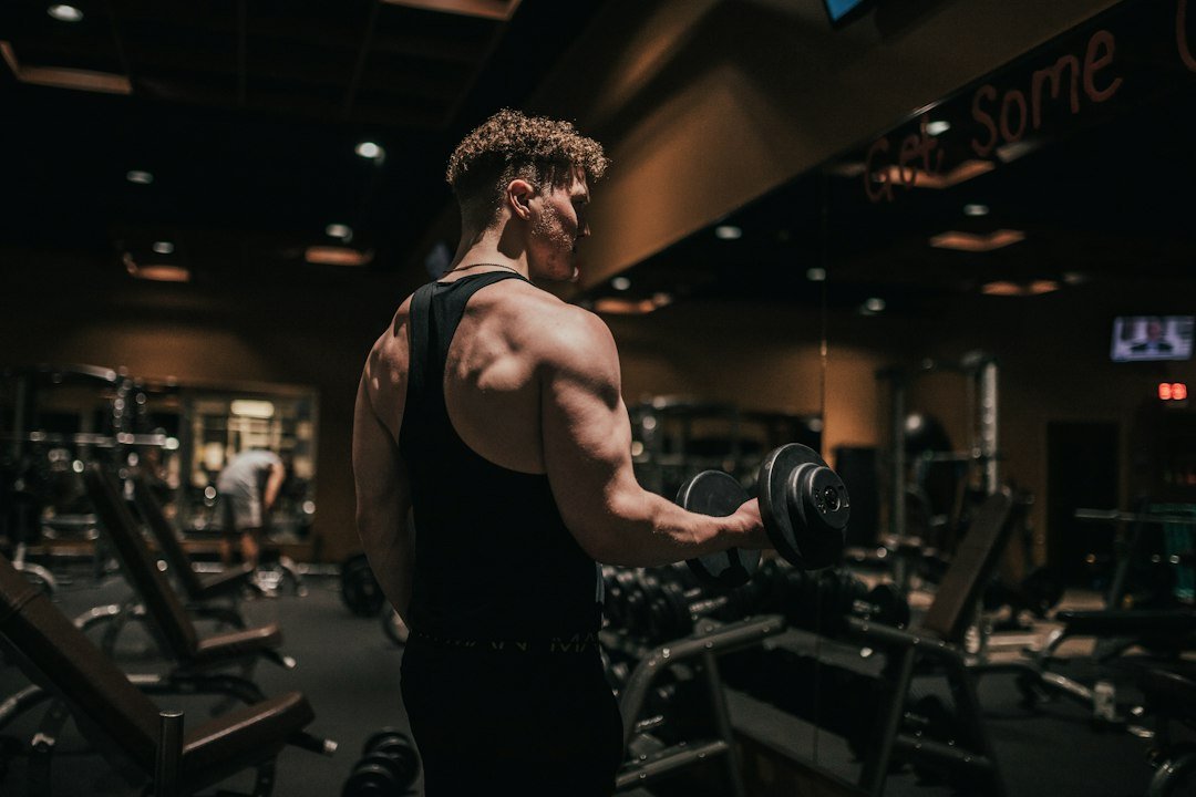 Hombre haciendo curl de bíceps con mancuerna en el gimnasio