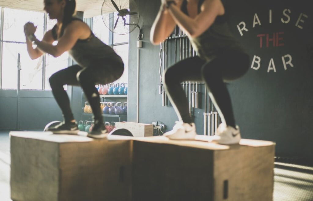 Dos personas haciendo salto al cajón en un gimnasio