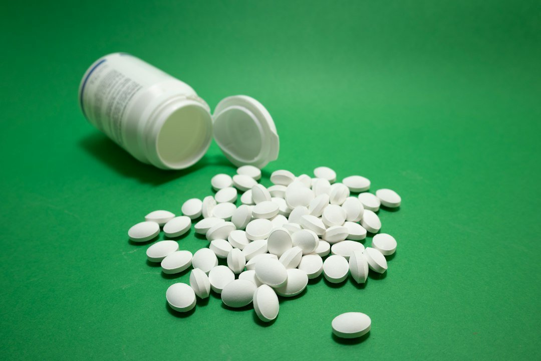 Comprimidos blancos de un suplemento junto a un bote abierto