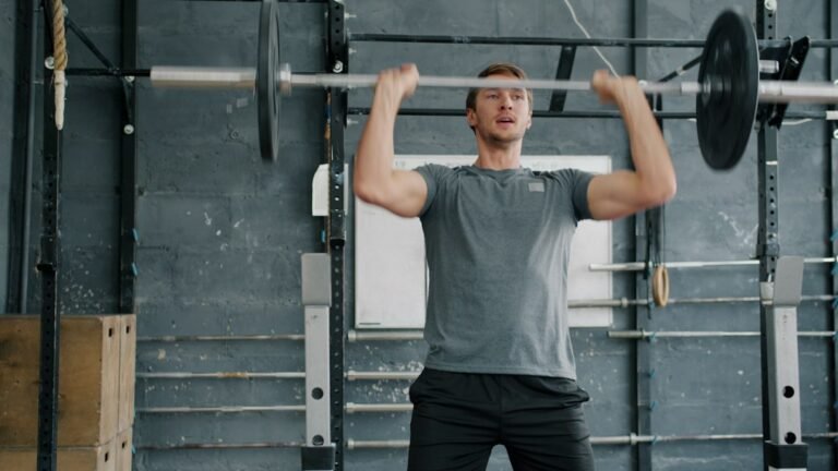 Hombre haciendo press militar con barra por encima de la cabeza en un rack de gimnasio