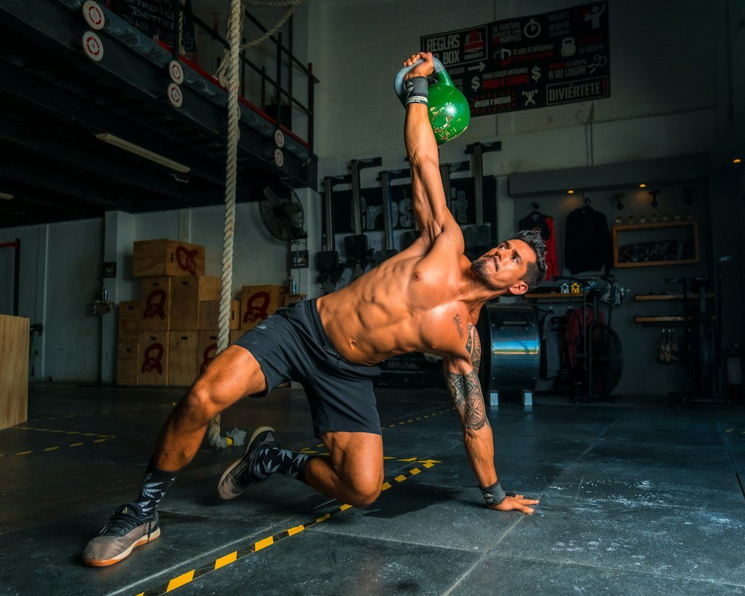 Hombre realizando un levantamiento turco (get-up) con kettlebell, ejercicio de entrenamiento funcional